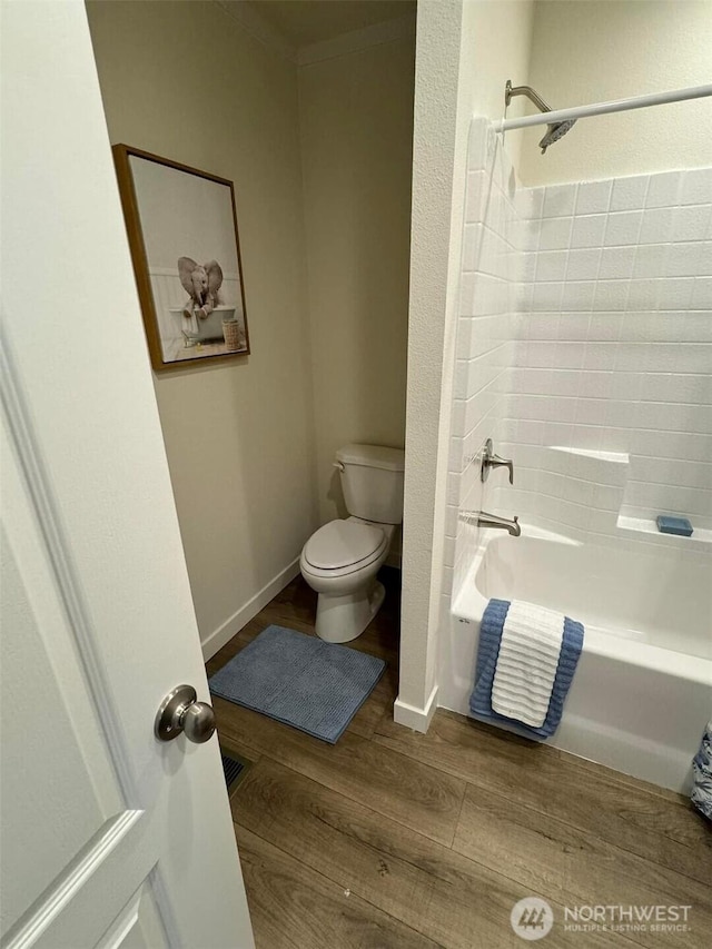 full bathroom with toilet, wood finished floors, visible vents, bathing tub / shower combination, and baseboards