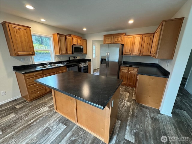 kitchen with appliances with stainless steel finishes, dark countertops, brown cabinets, and a kitchen island