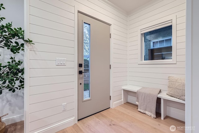 foyer entrance with light wood finished floors and wooden walls