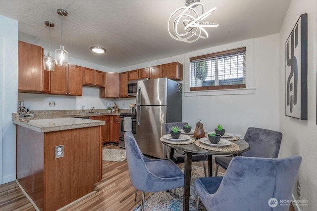 kitchen featuring light countertops, brown cabinetry, decorative light fixtures, and stainless steel appliances