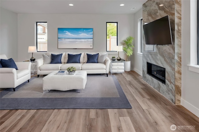 living area featuring baseboards, recessed lighting, wood finished floors, and a premium fireplace