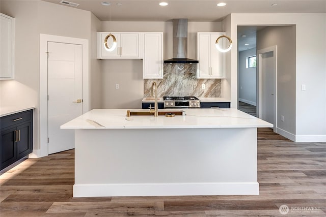 kitchen with wall chimney range hood, white cabinets, backsplash, and stainless steel range with gas cooktop