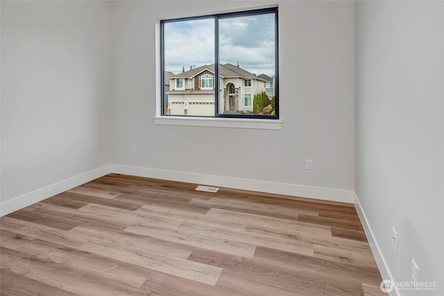 unfurnished room featuring wood finished floors, visible vents, and baseboards