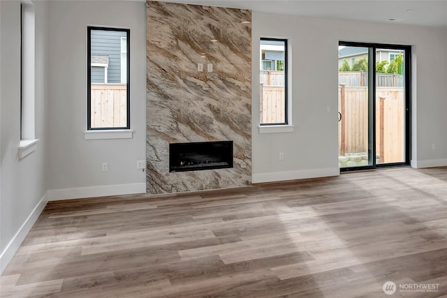 unfurnished living room with baseboards, a fireplace, and wood finished floors