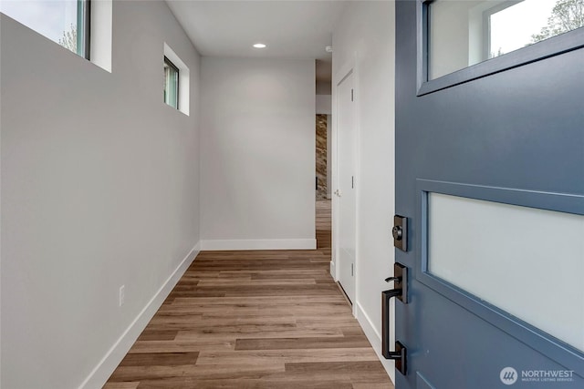 doorway featuring baseboards, plenty of natural light, recessed lighting, and wood finished floors