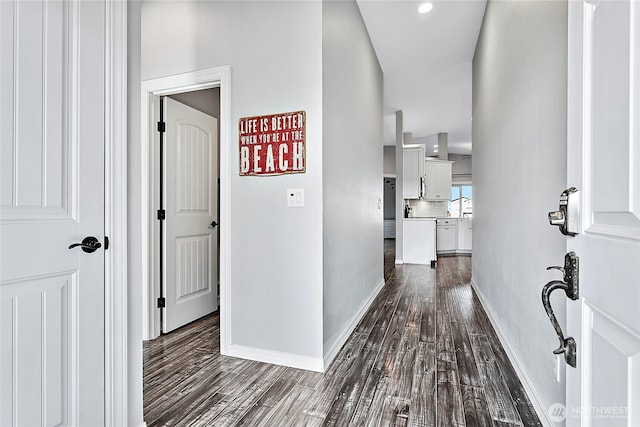 hallway featuring baseboards and dark wood-style flooring