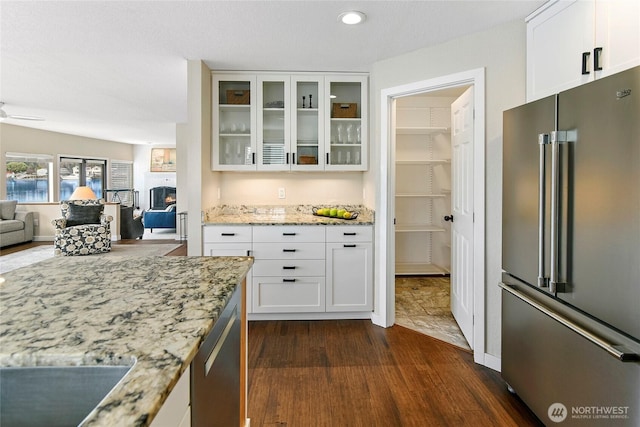 interior space featuring white cabinetry, light stone counters, glass insert cabinets, and stainless steel appliances