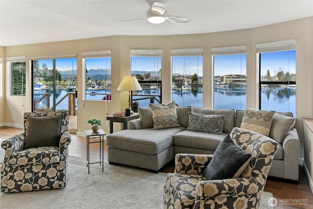 sunroom featuring a ceiling fan and a water view