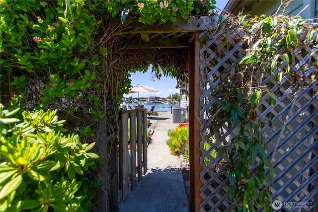 view of gate with central air condition unit and a water view