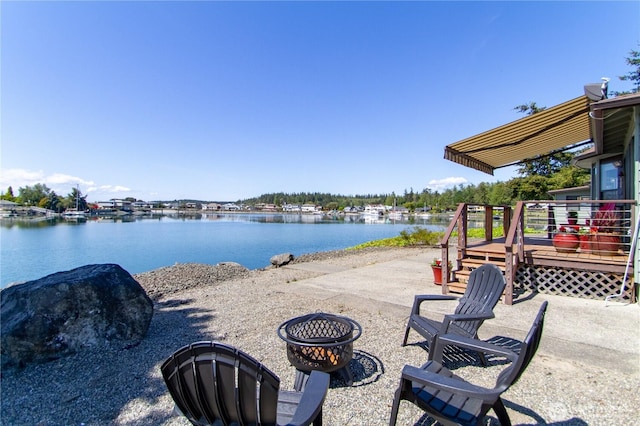 view of patio with a fire pit and a deck with water view