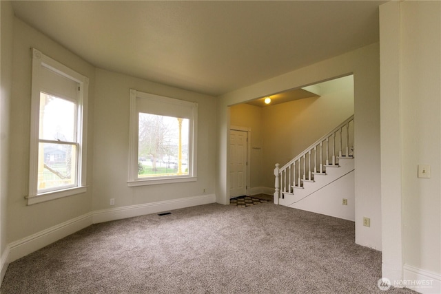 spare room featuring visible vents, carpet flooring, plenty of natural light, and stairway