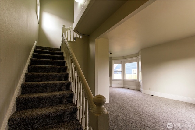 staircase featuring baseboards and carpet flooring