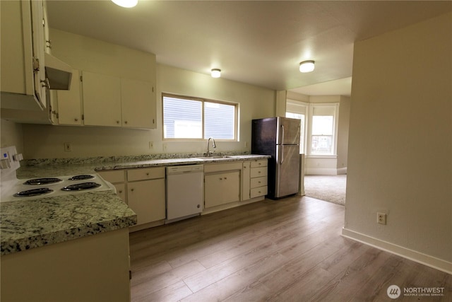 kitchen featuring white appliances, baseboards, light wood-style flooring, light stone countertops, and a sink