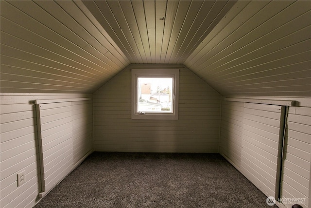 additional living space with lofted ceiling, wood walls, wood ceiling, and dark colored carpet