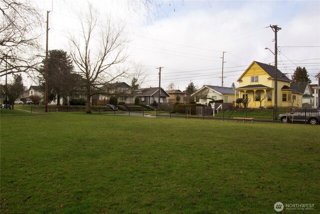 view of home's community with a yard, a residential view, and fence