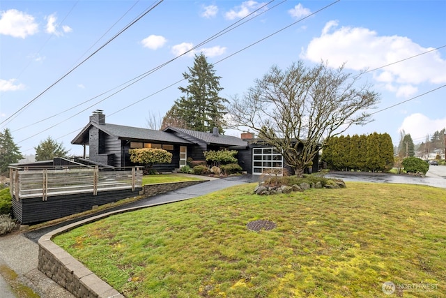 mid-century inspired home with aphalt driveway, a chimney, and a front lawn