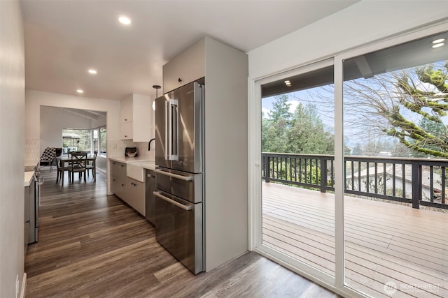 kitchen with tasteful backsplash, dark wood finished floors, high quality fridge, light countertops, and white cabinetry