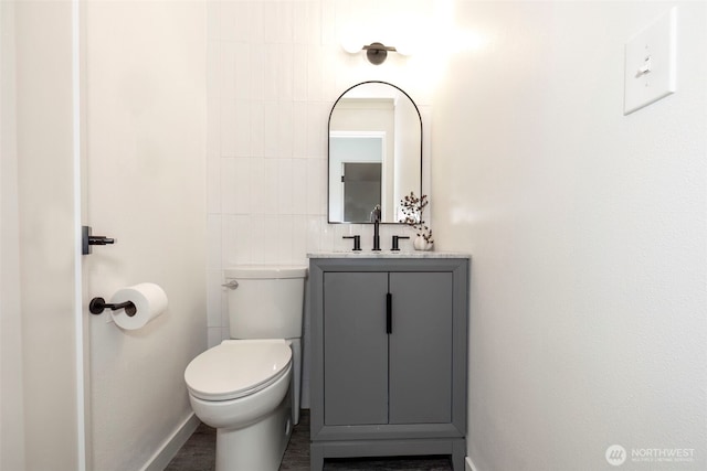 bathroom featuring vanity, toilet, and baseboards