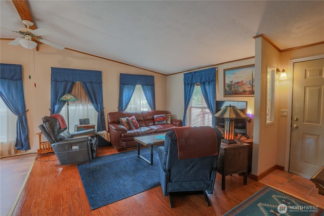 living area with wood finished floors, a ceiling fan, baseboards, vaulted ceiling, and ornamental molding