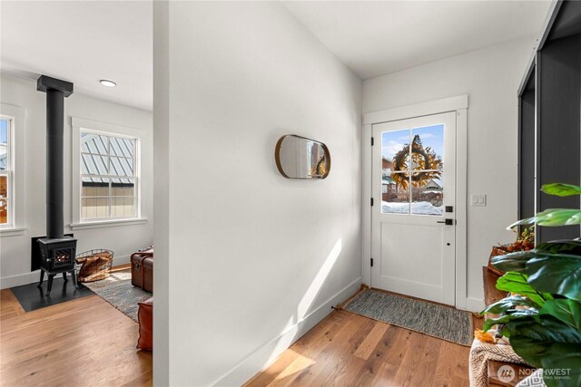 foyer with a wood stove, baseboards, and wood finished floors