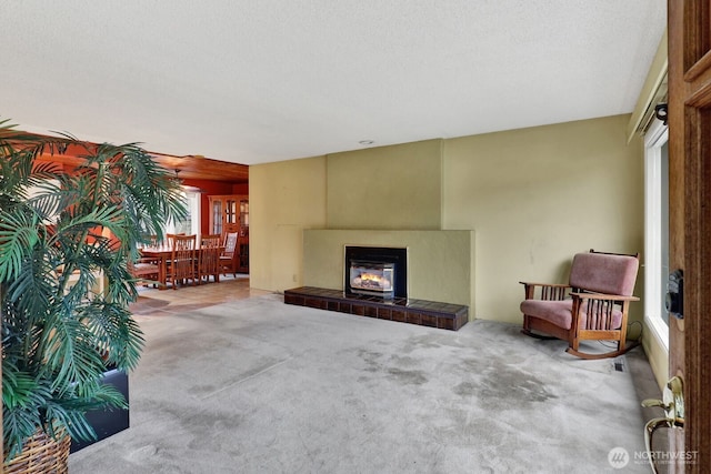 carpeted living room featuring a textured ceiling and a tile fireplace