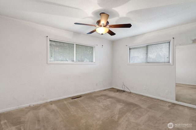 spare room with light colored carpet, ceiling fan, visible vents, and baseboards