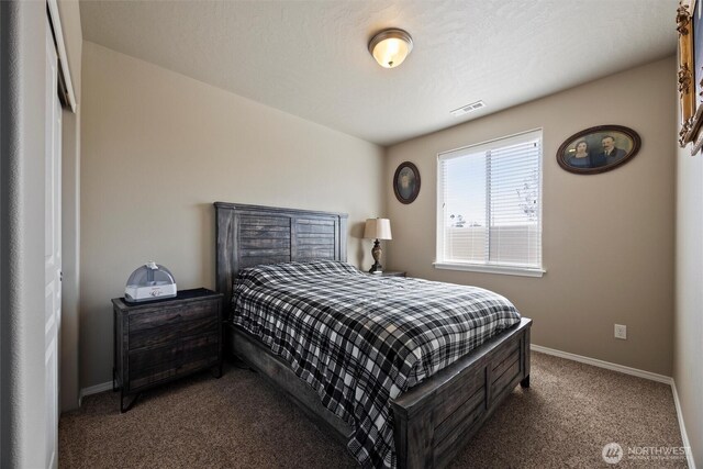 bedroom with baseboards, visible vents, and dark carpet