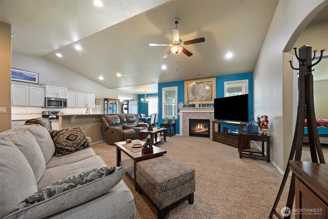 living area with arched walkways, lofted ceiling, recessed lighting, light carpet, and a ceiling fan