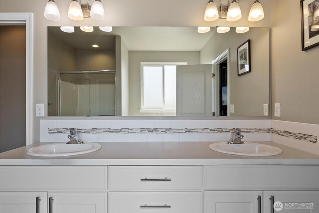 bathroom featuring double vanity, a stall shower, and a sink