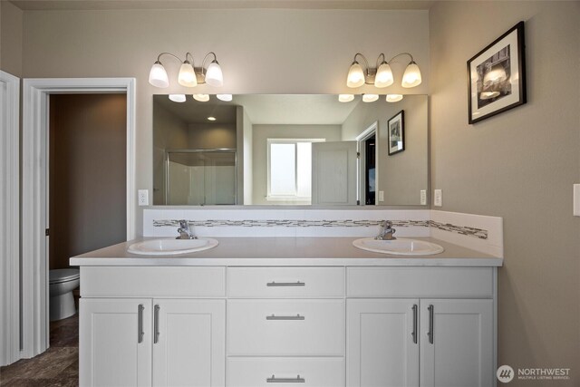 bathroom with a stall shower, a sink, toilet, and double vanity