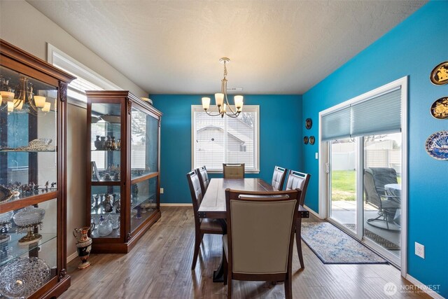 dining space with baseboards, a chandelier, and dark wood-style flooring