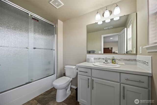 bathroom featuring enclosed tub / shower combo, toilet, vanity, and visible vents