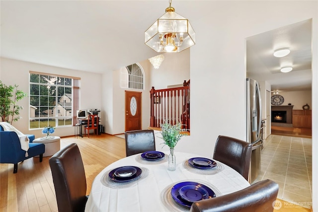 dining area featuring light wood-type flooring, a lit fireplace, and a chandelier