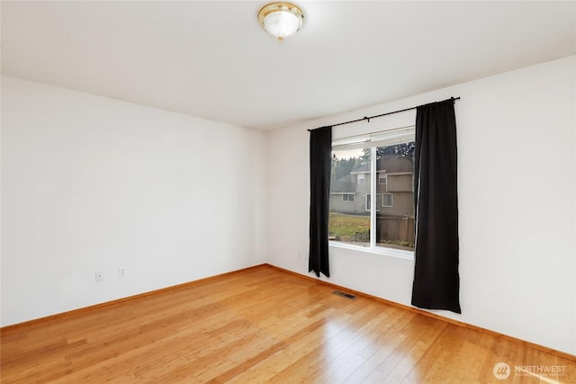 unfurnished room with visible vents, baseboards, and wood finished floors