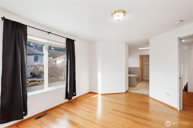 unfurnished room featuring wood finished floors, visible vents, and baseboards