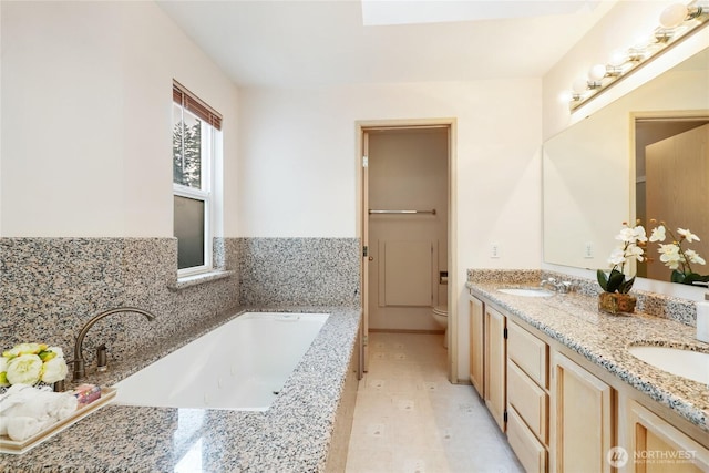 bathroom with a bath, a sink, toilet, and double vanity