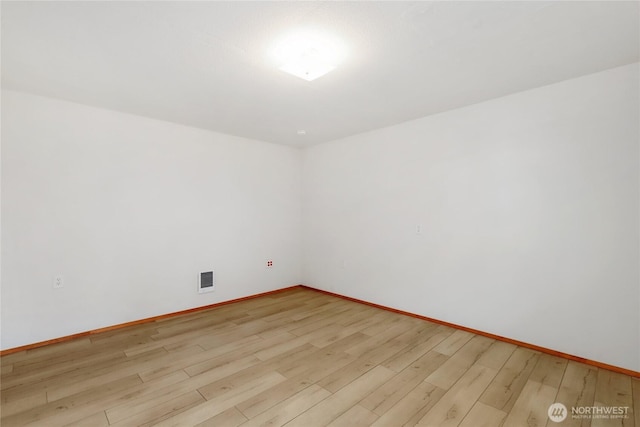 spare room with light wood-style flooring, visible vents, and baseboards