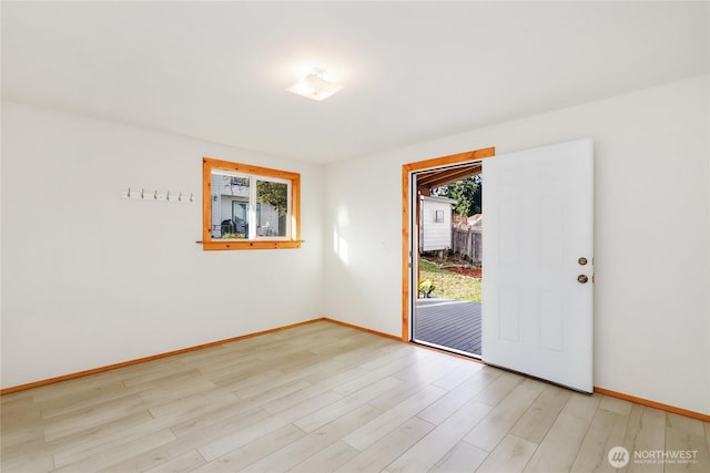 unfurnished room featuring a healthy amount of sunlight, light wood-style floors, and baseboards