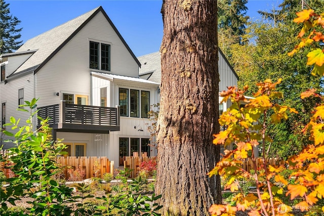 rear view of property with a balcony, fence, and board and batten siding