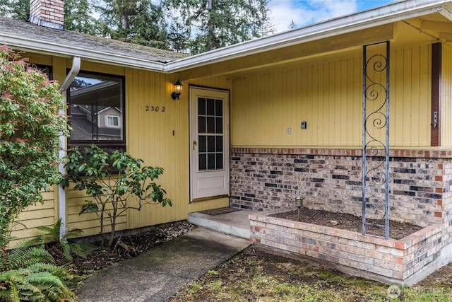 property entrance featuring brick siding and a chimney