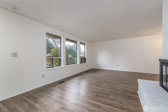 unfurnished living room featuring dark wood-style floors, a glass covered fireplace, and a textured ceiling