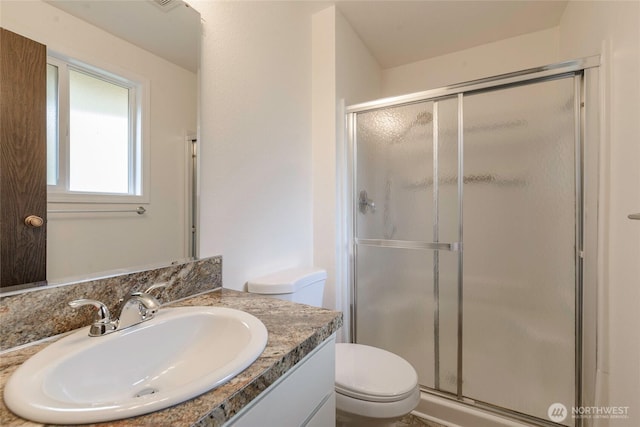 bathroom featuring toilet, a stall shower, and vanity