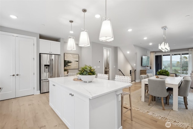 kitchen featuring a center island, white cabinets, stainless steel fridge, and decorative light fixtures