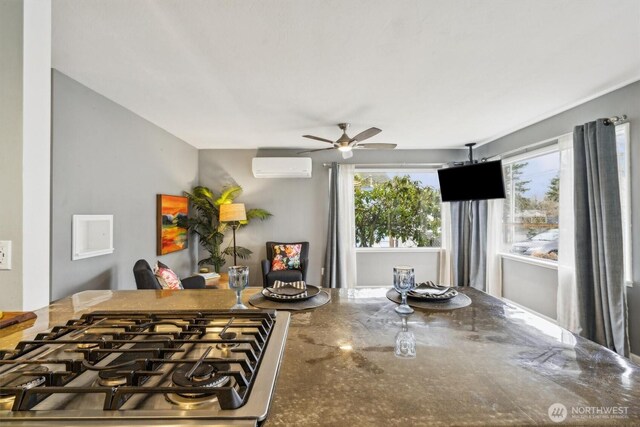 kitchen with ceiling fan, a wall unit AC, and gas stovetop