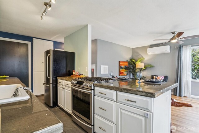 kitchen featuring a wall mounted AC, appliances with stainless steel finishes, white cabinets, a kitchen island, and a sink