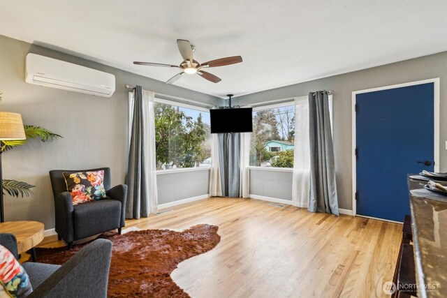 living area featuring ceiling fan, baseboards, wood finished floors, and a wall mounted air conditioner