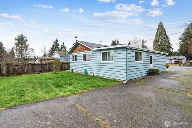 view of property exterior with fence and a lawn