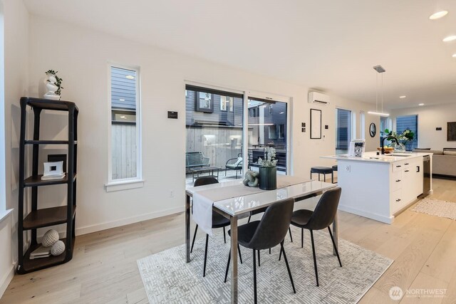 dining space featuring light wood-type flooring, an AC wall unit, baseboards, and recessed lighting