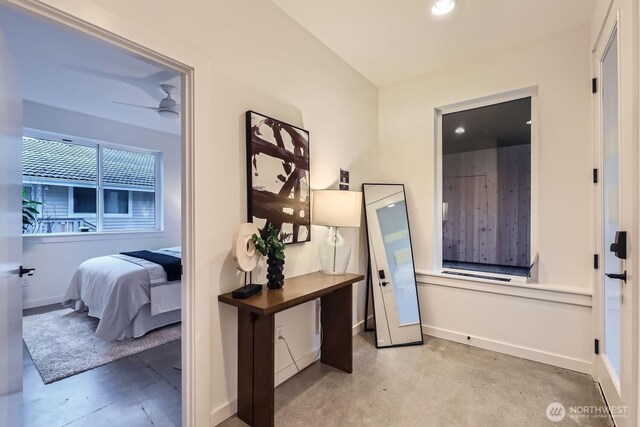 hallway featuring concrete flooring, recessed lighting, and baseboards