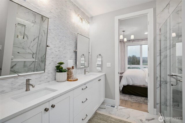 bathroom featuring marble finish floor, a marble finish shower, a sink, and ensuite bathroom